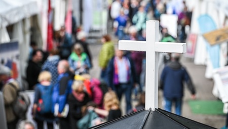 Ein weißes Kreuz, darunter Teilnehmer des 103. Katholikentags auf der Kirchenmeile, am 30. Mai 2024 in Erfurt.
