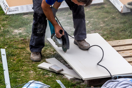 Fliesenleger bei der Arbeit / Erwin Wodicka - wodicka@aon.at, Erwin Wodicka Ein Fliesenleger bei der Arbeit. Zerschneidet Platten mit einer Trennscheibe