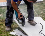 Ein Fliesenleger bei der Arbeit. Zerschneidet Platten mit einer Trennscheibe